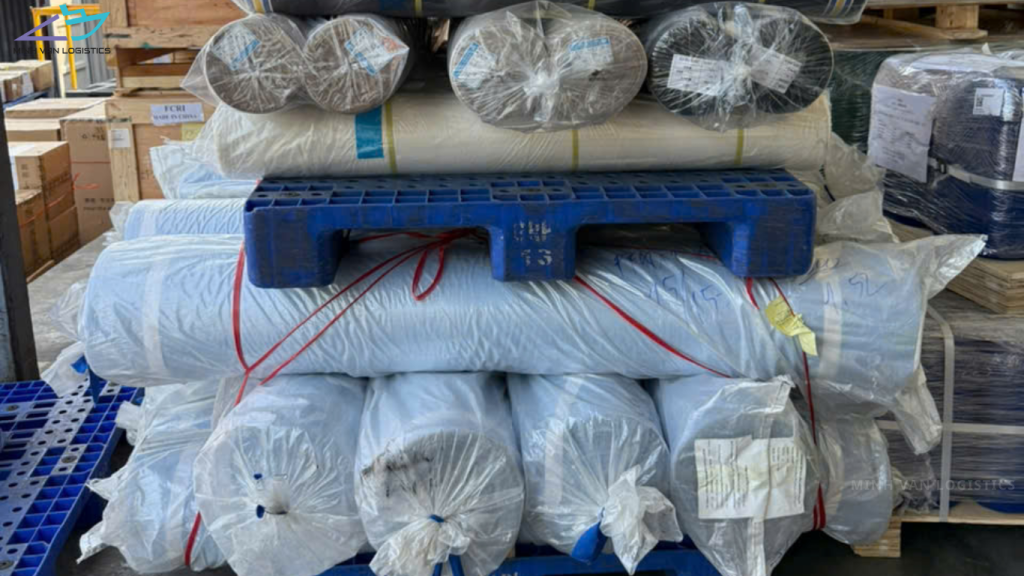 Wrapped textile rolls secured on a pallet in a warehouse